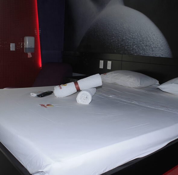 Moderno cuarto de motel con cama impecable, toallas enrolladas y decoración contemporánea.