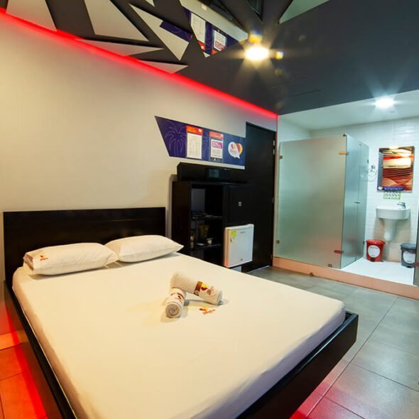 Elegante habitación de motel con cama amplia, iluminación sutil y baño en suite con jacuzzi incorporado.