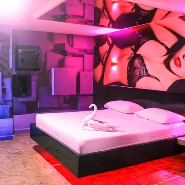 Habitación de motel chic en Bucaramanga, deslumbra con un jacuzzi, luces rojas seductoras, amplia cama y una provocativa obra de arte.