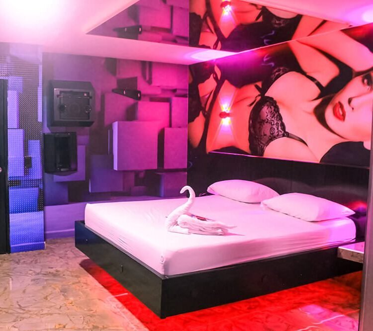 Habitación de motel chic en Bucaramanga, deslumbra con un jacuzzi, luces rojas seductoras, amplia cama y una provocativa obra de arte.