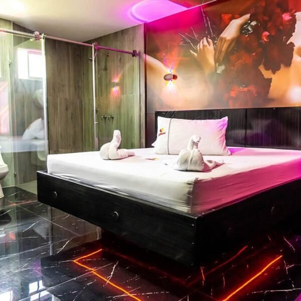 elegante habitación de motel en Bucaramanga, con cama grande, decoración mural artística, luz ambiental y baño de diseño abierto