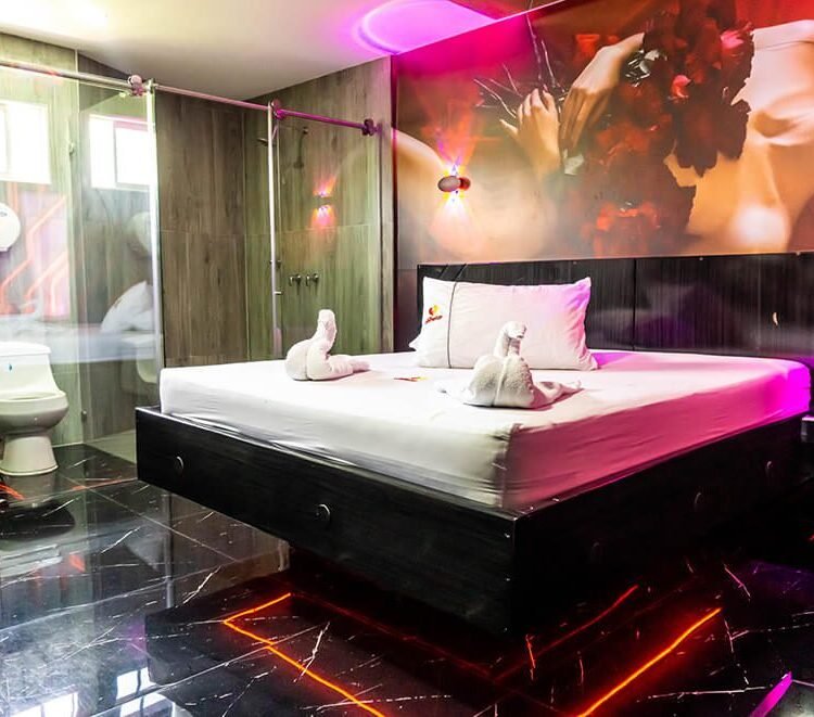 elegante habitación de motel en Bucaramanga, con cama grande, decoración mural artística, luz ambiental y baño de diseño abierto