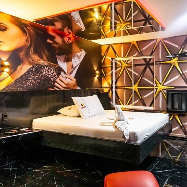 Vanguardista y audaz habitación de motel con jacuzzi, cama amplia, paredes con patrones geométricos y arte temático.