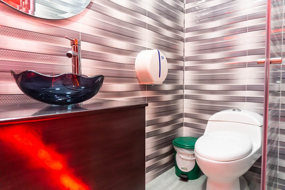Interior de un moderno baño en un motel de Bucaramanga, con una singular pileta tipo barco y paredes con diseño a rayas.