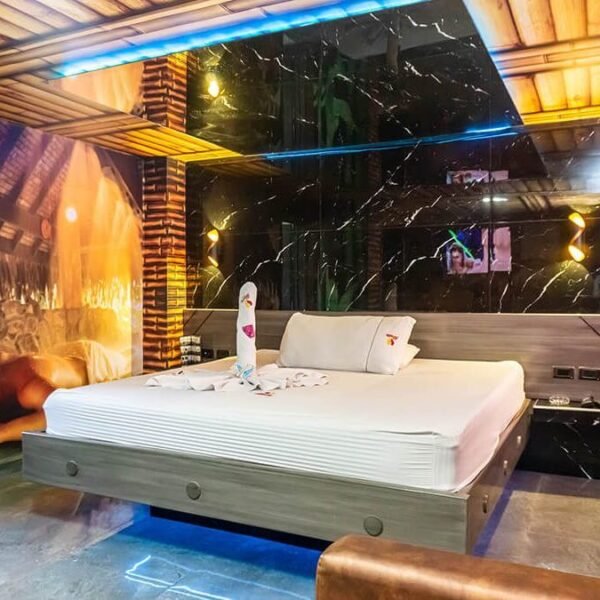 Lujoso motel en Bucaramanga con cama grande, jacuzzi brillante bajo iluminación LED y una fascinante decoración mural temática.