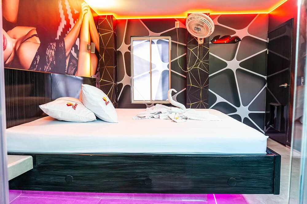 Dormitorio moderno y artístico en Bucaramanga; Destaca su iluminación vibrante, diseño mural excepcional y la bienvenida con toallas de baño en forma de cisne sobre la cama junto a un jacuzzi.