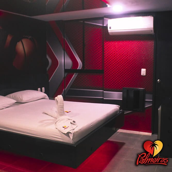 Un dormitorio moderno en un motel de Bucaramanga destaca por su pared roja, literatura, gráfica temática grande, aire acondicionado y televisor plano.