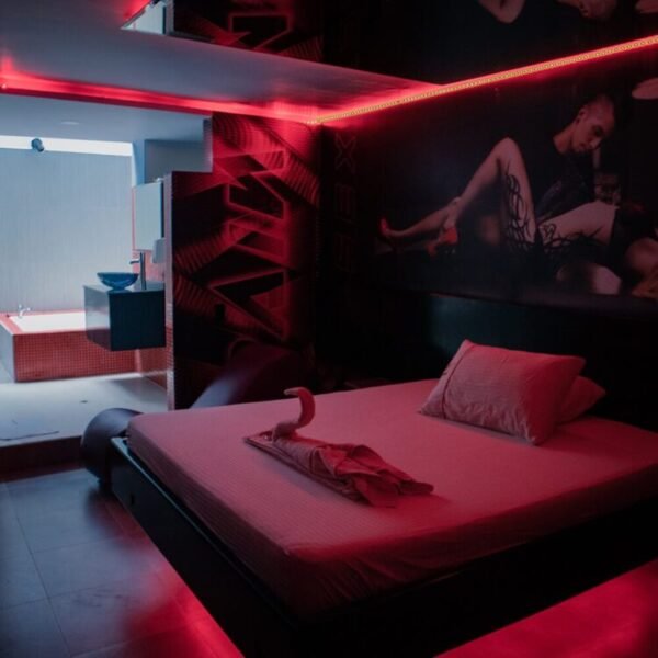 Rojo seductor ilumina la estancia monocromática con cama grande y arte mural en un motel con jacuzzi.