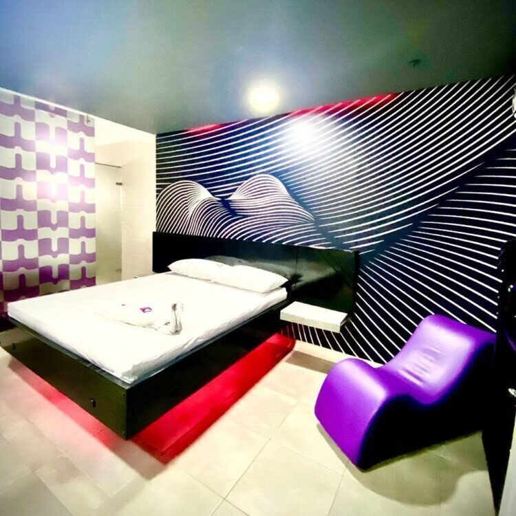 Colorido cuarto de motel en Bucaramanga: diseño moderno, cama con luz roja, patrones geométricos en pared y atrevidos acentos morados; Incluye jacuzzi.