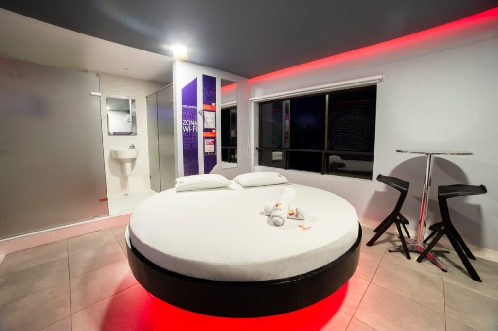 Diseño vanguardista de motel en Bucaramanga: camas redondas, luces rojas y baño con jacuzzi.