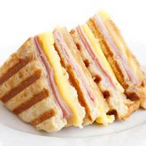 Un tentador sándwich de jamón y queso a la parrilla, cortado en dos mitades, descansa sobre un plato en el motel.